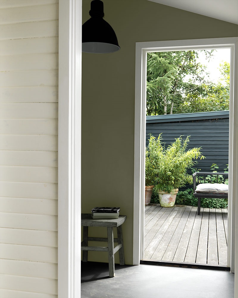 Den grønne væg og træbænken skaber harmoni mellem bolig og natur